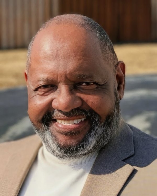 Pastor Jasper McNutt, smiling, in a tan jacket and cream turtleneck.